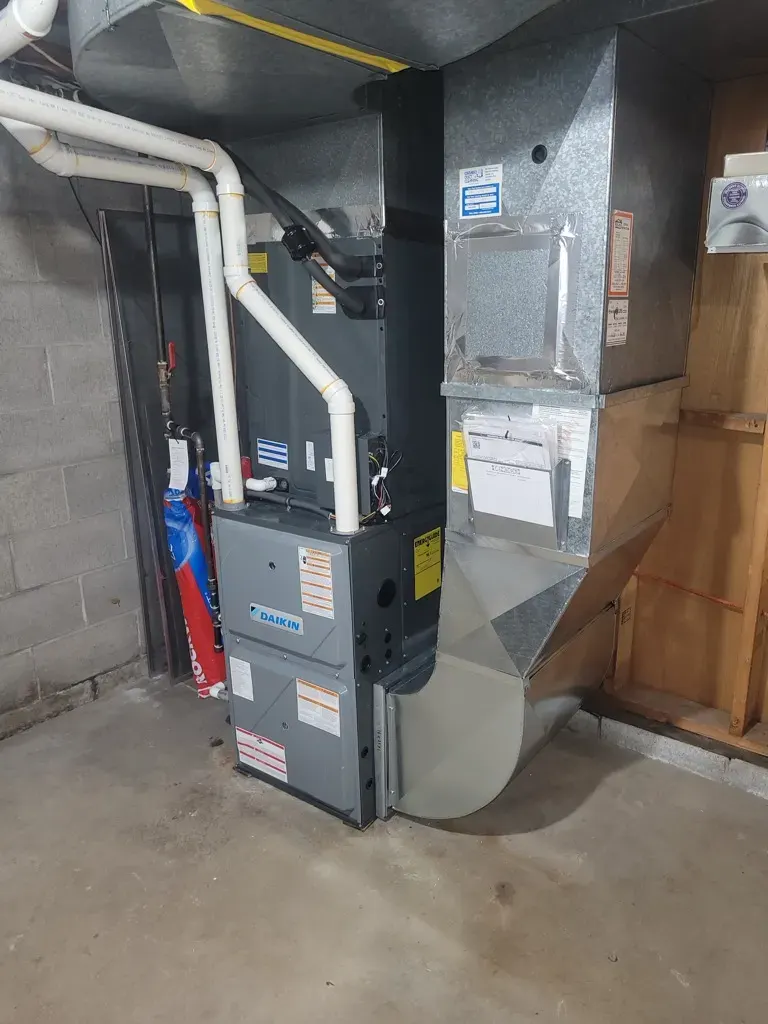 A new Daikin furnace and air handler installed with ductwork in a basement mechanical room