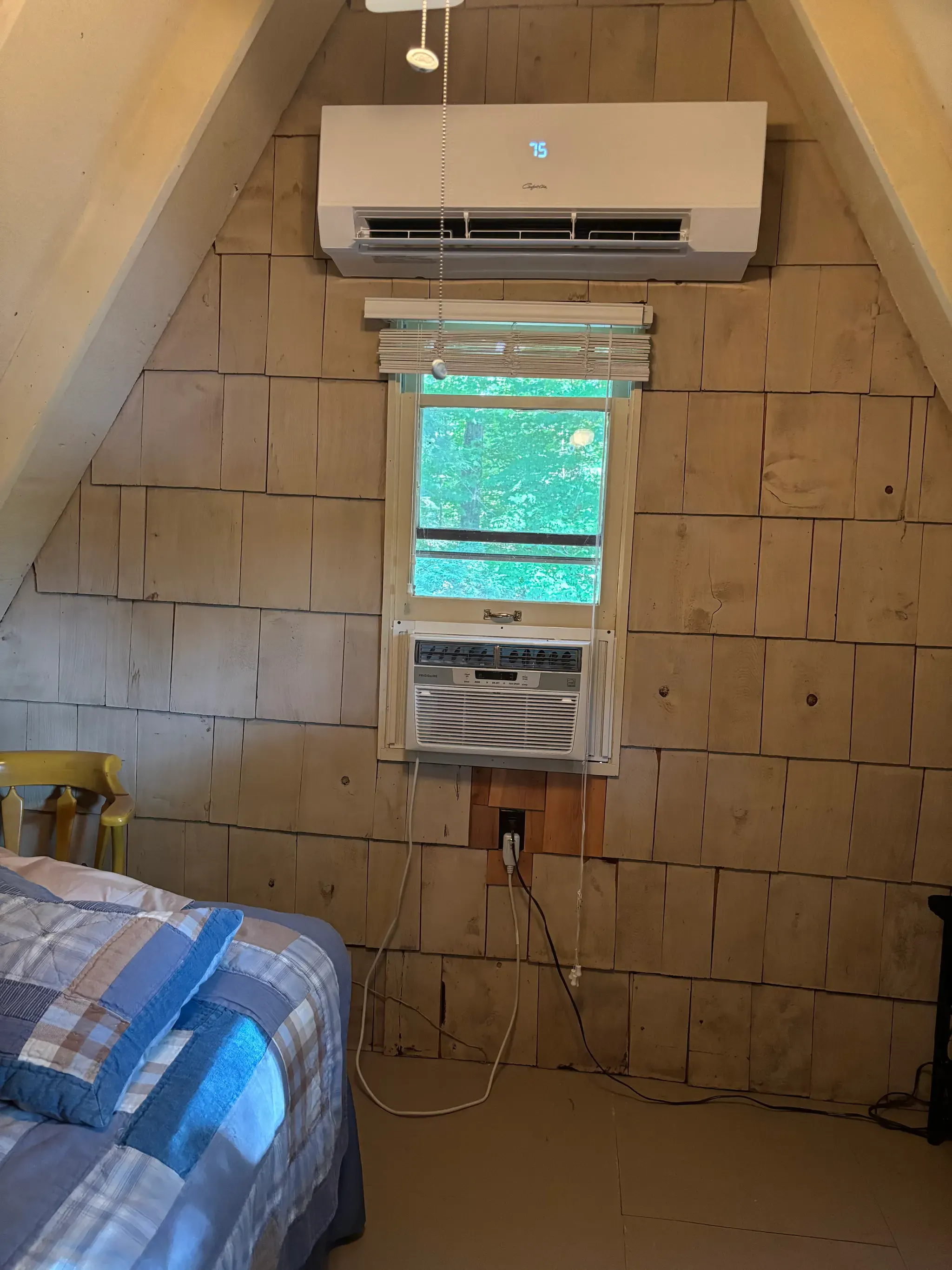 A ductless mini-split head mounted high on a wood-panel wall